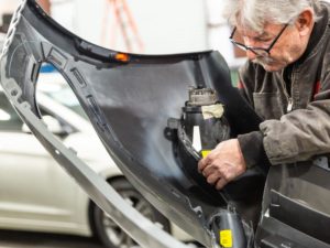 auto body repair tech working on bumper